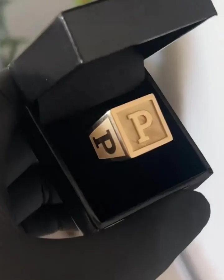 Anel quadrado em ouro 18k com a letra P em relevo, girando no estojo