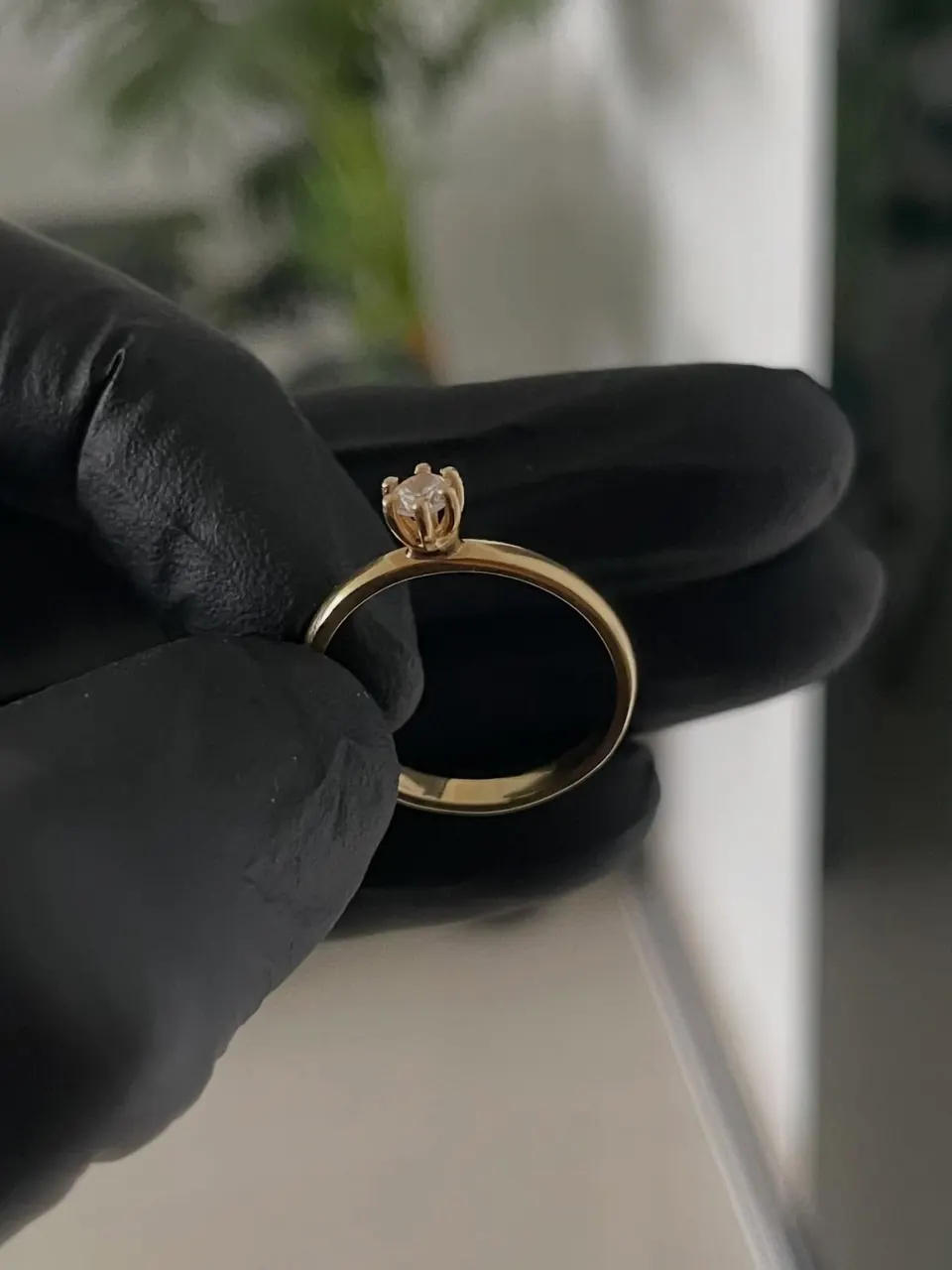 Anel solitário clássico em ouro 18k segurado por luva preta